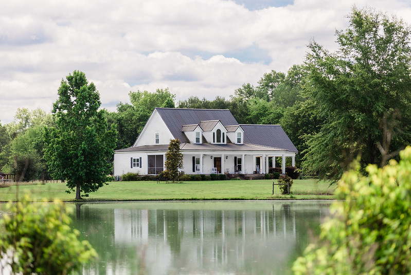  White house on manicured lawn near a pond 