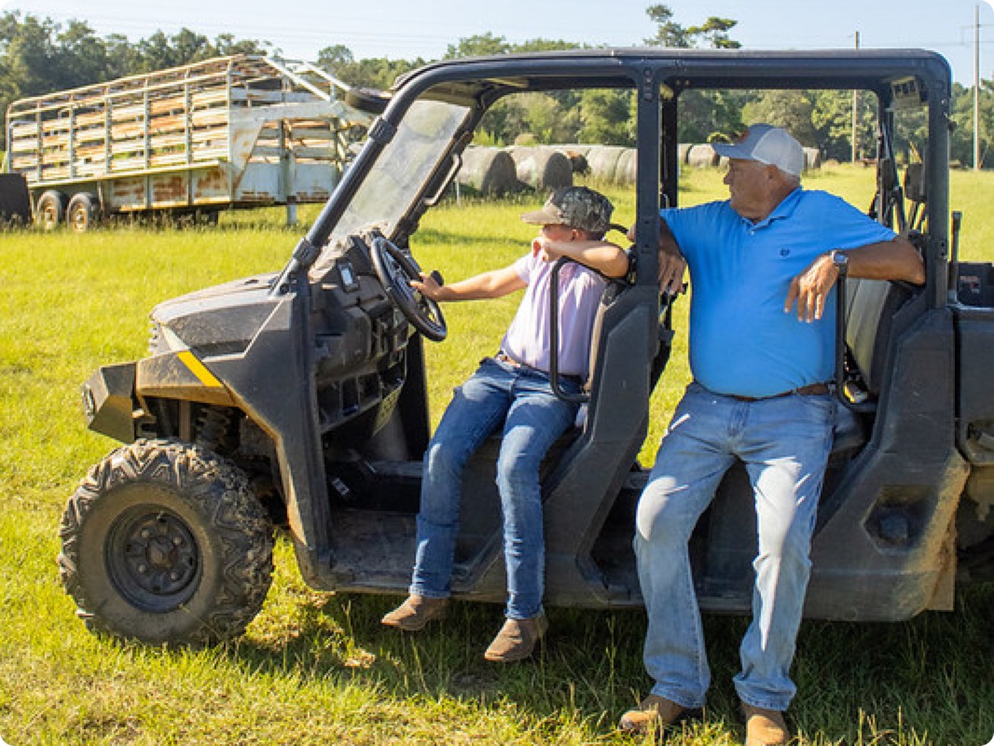Man and child sitting in a cart overlooking the farm
