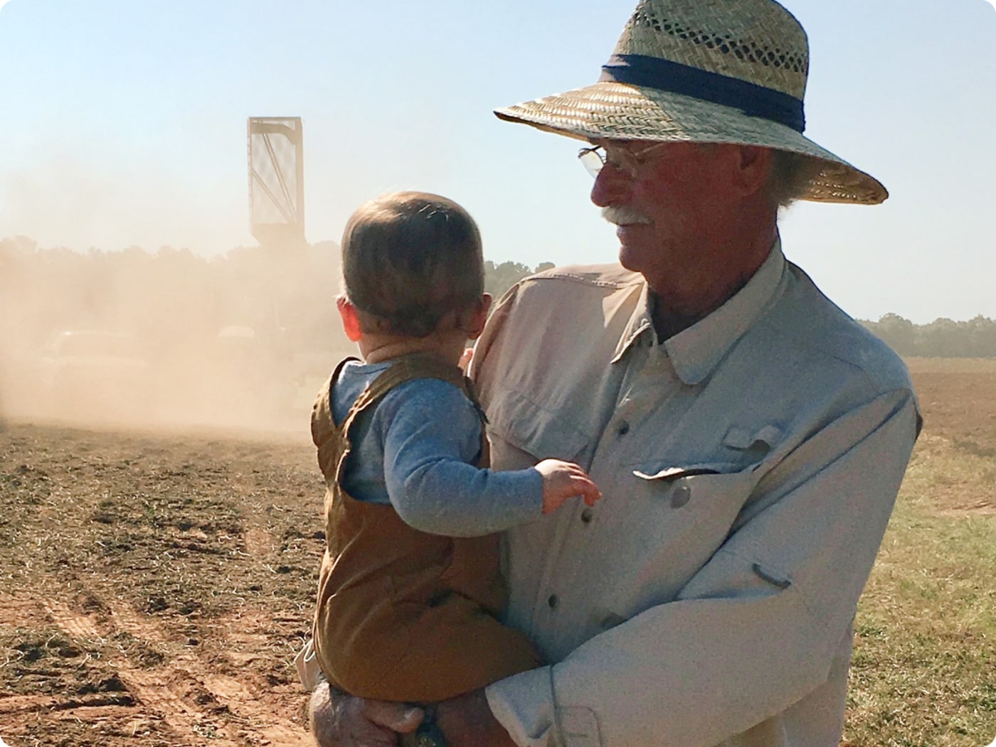  Man holding a baby in a field 